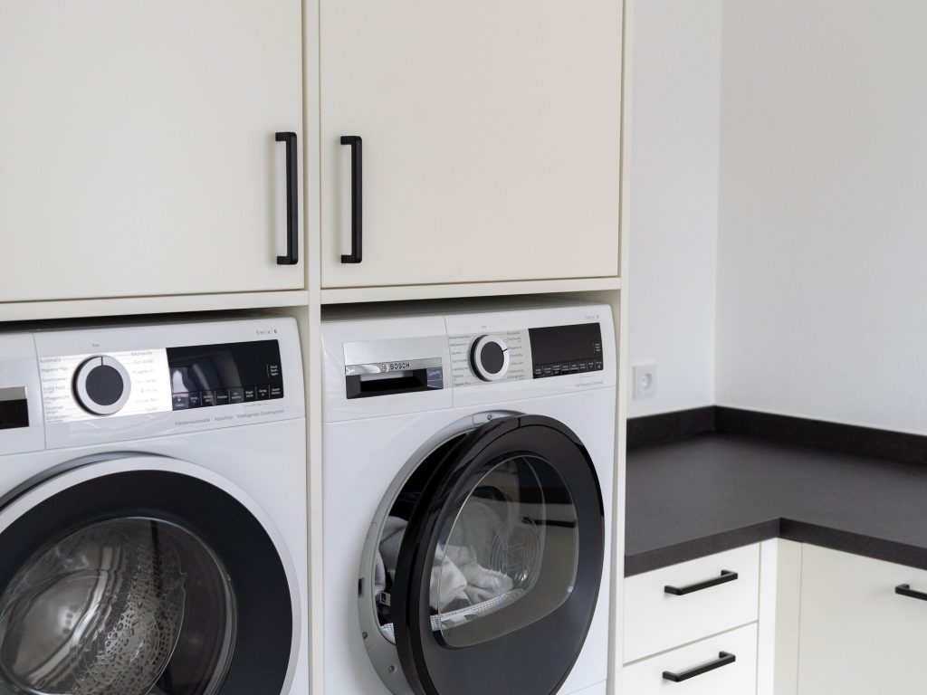 Hauswirtschaftsraum mit Waschmaschine, Trockner und durchgehender dunkler Arbeitsplatte – Schreinerei Niederreiter