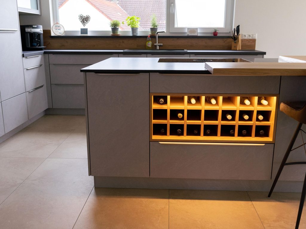 Kochinsel mit beleuchtetem Weinregal aus Holz – Schreinerei Niederreiter