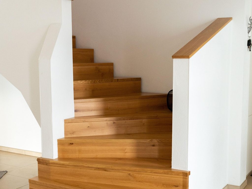 Gewendelte Treppe aus Eiche mit weißen Wangen und Holzhandlauf – Schreinerei Niederreiter